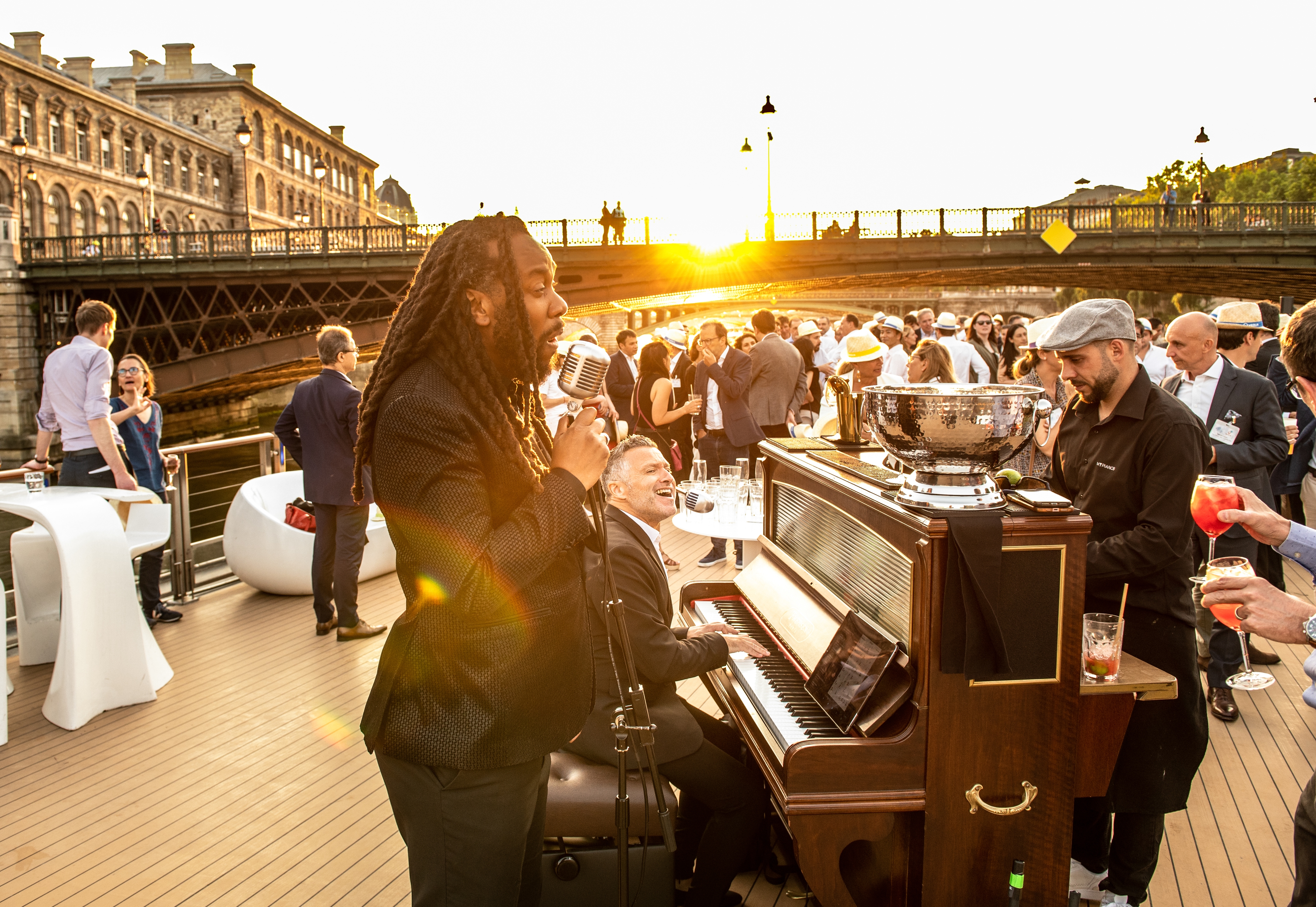 Un barman préparant des cocktails sophistiqués chez un particulier, avec divers ingrédients et bouteilles en arrière-plan